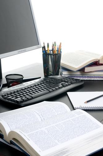 Piles of books open with a computer. Working on a research paper. Photo courtesy of Shutterstock.
