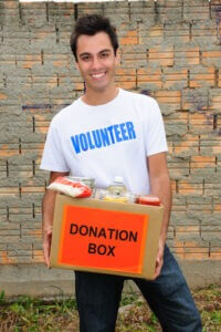 Young man carrying a box with food donations.  Photo courtesy of Shutterstock.
