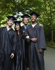 Four college graduates standing and smiling