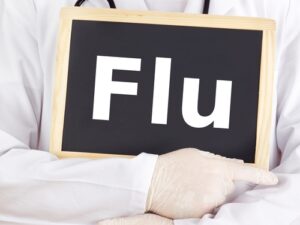 Doctor showing the word Flu on a chalkboard