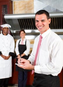 Smiling male restaurant manager with kitchen staff