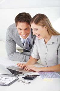 Smiling man and woman finding a job online, using a laptop computer