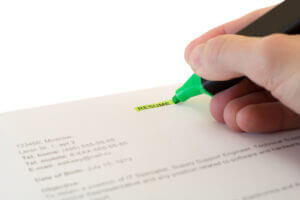 Someone highlighting the word "resume" on a piece of paper.