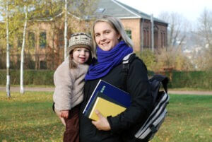 Smiling mother with school belongings carrying her daughter