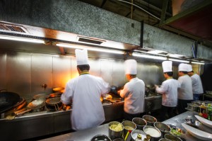 Chefs working in crowded kitchen with narrow aisle