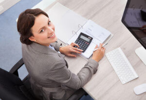 Young female accountant smiling while calculating bills