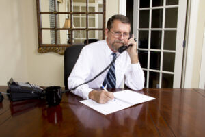 Loan officer at bank having a phone interview with a businessman about his needs