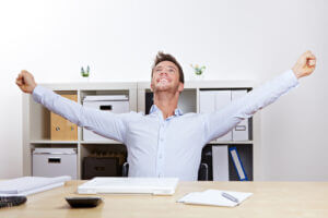 Happy, successful businessman showing cheer with clenched fists at work