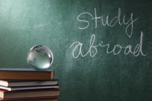 Glass globe on a book with study abroad in the background