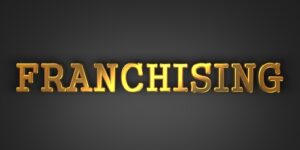 The word franchising in gold with black background
