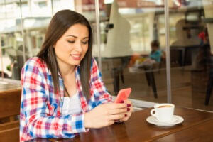 Young woman in cafe restaurant with phone and coffee