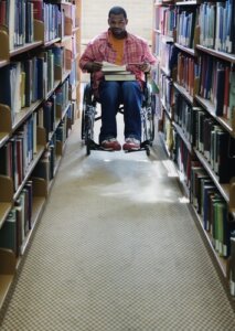 Male college student in wheelchair at library 