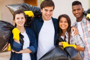 Cheerful young volunteers with garbage bag after cleaning the streets