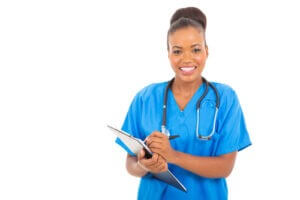 Happy medical intern doctor writing on clipboard