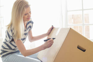 Woman labeling moving box at home