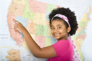 Girl pointing to map of United States and smiling at viewer