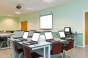 An IT classroom laptops on the desks and an interactive white board with blank screens to add your own image or text