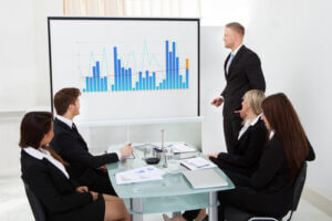 Businessman giving presentation on projector screen to colleagues in office