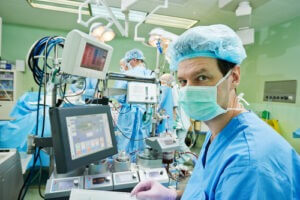 Surgery assistant perfusionist working with artificial cardiac valve at operation in cardiology clinic