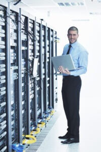 Young engineer business man with thin modern aluminium laptop in network server room