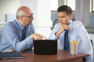 senior and junior businessman discuss something during their meeting, office background