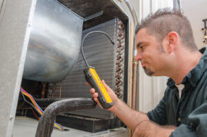 An HVAC technician searching for a refrigerant leak on an evaporator coil courtesy of Shutterstock.com