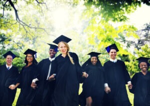 Smiling college students holding hands at graduation courtesy of Shutterstock.com
