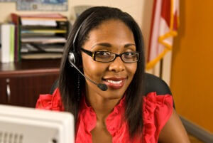 Receptionist wearing a headset and glasses smiling courtesy of Shutterstock.com