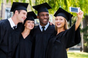 Four college graduates in graduation gowns standing close to each other and making selfie courtesy of Shutterstock.com