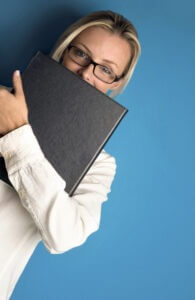 Woman with glasses covering her mouth with a document photo by StockUnlimited.com